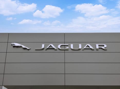 Filderstadt, Germany - October 03, 2019: Jaguar brand logo on bright blue sky background located on its dealer Entrance in showroom of dealership office building.