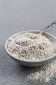 Glutenfree buckwheat flour for baking in the bowl on grey background