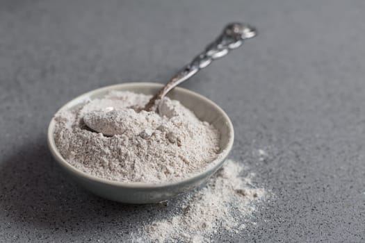 Glutenfree buckwheat flour for baking in the bowl on grey background