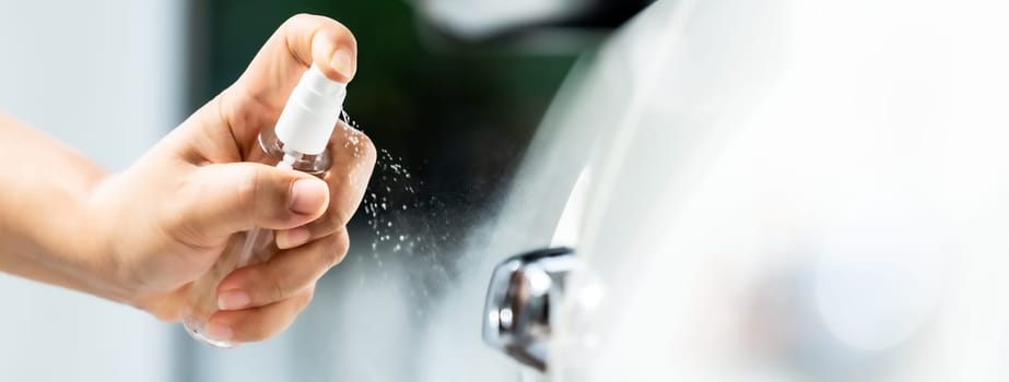 panoramic web banner,  car cleaning using hand spraying alcohol, disinfectant spray on car door handle for safety prevent and protect from infection of virus and germ Covid-19 coronavirus pandemic.