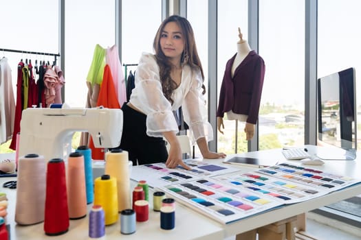 Portrait of young adult asian fashion designer working from home with colour palette as owner entrepreneur at her atelier studio. Using for entrepreneur Small Business startup concept.