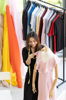 Top view of young adult asian fashion designer using measuring tape to measure dress arm at her atelier studio as sole owner. Using for entrepreneur small business startup concept.