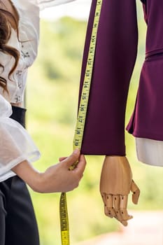 Close-up young adult asian fashion designer using measuring tape to measure suit arm at her atelier studio as sole owner. Using for entrepreneur small business startup concept.