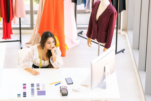 Top view of young adult asian fashion designer drawing and sketching her work at home as atelier studio with colour palette. Using for entrepreneur small business startup concept.