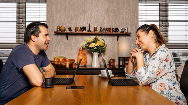 Men and woman, couple, talking and working on computers from comfort of their home during covid 19 or coronavirus pandemics, lockdown and quarantine