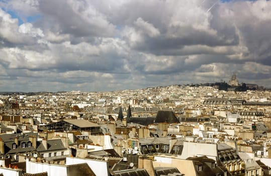 The roofs of Paris under a stormy sky. In the distance the Sacre Coeur (Paris France)