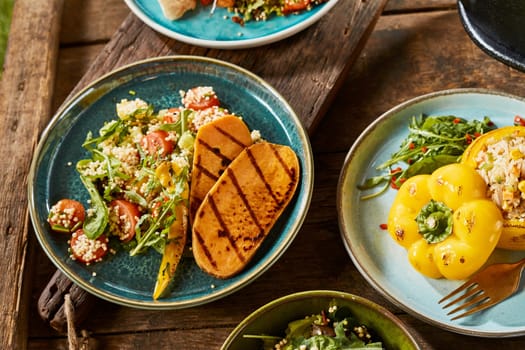 A close up of various gourmet vegetarian dishes on a rustic timber table.
