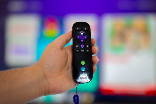 Calgary Alberta, Canada. May 5, 2020. A person holding a Roku remote control with a screen tv on the background