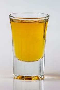Close up vertical view of a liquor shot drink on a white background