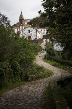 San Andres de Teixido, Spain - 01, 04, 2017: A winding, cobbled path leads to the chapel of San Andres de Teixido between trees and vegetation