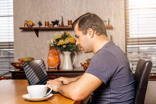 Middle age man working on document on the laptop from comfort of his home at sunny day during covid 19 or coronavirus pandemics and quarantine