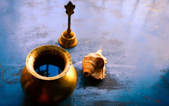 Close up Still Life of antique Holi water pot and bell and Conch shell on rustic floor. Faith, Tradition, Spirituality, Prayer, symbols of peace and Religious Themes. Arts and culture background concept. Copy space room for text for massage.