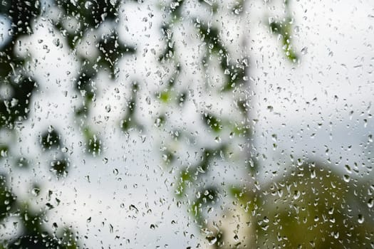 Raindrops on the window pane. Blurred background outside the window in the rain.