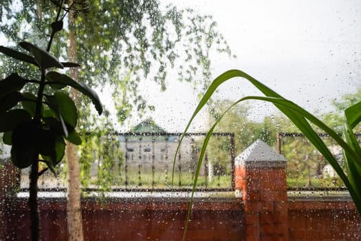 Raindrops on the window pane. Blurred background outside the window in the rain.