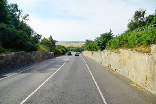 Asphalt road on which cars go. Landscape view from the cab