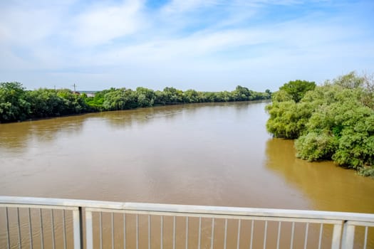 Passing over the bridge over the river. The landscape of the river, the surface and the trees of the river's waterplain.