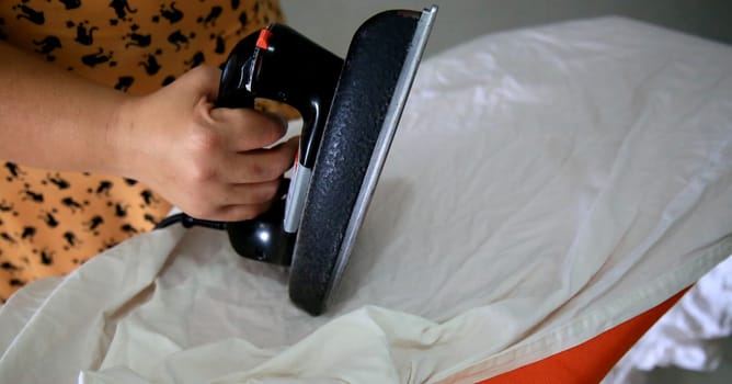 salvador, bahia / brazil - may 8, 2020: a person is seen using an iron on an ironing board in the city of Salvador.