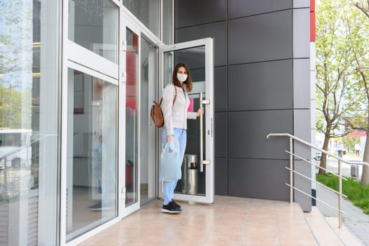 Girl walks out of the store wearing a medical mask with shopping