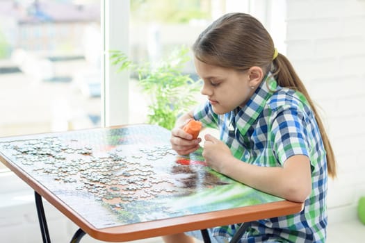 Girl at home by the window collects puzzles on his day off