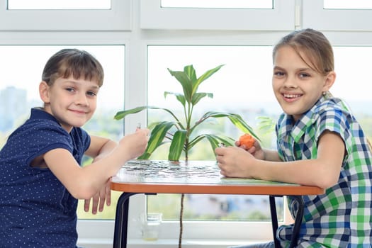 Children assemble a puzzle at home and happily look into the frame