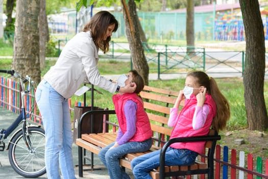 Mom on a walk puts on protective medical masks on the girl's face