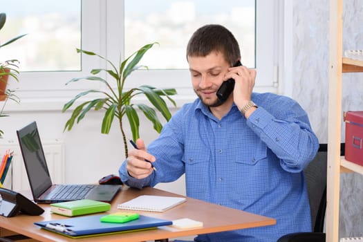 Office specialist talking on the phone and taking notes in a notebook
