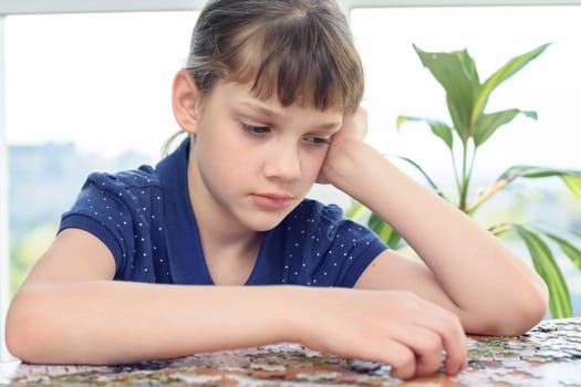 Tired girl collects puzzle for a long time