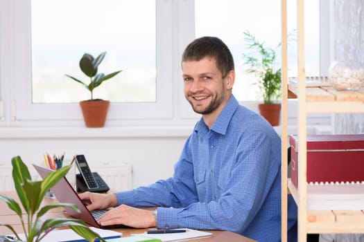 Successful young man in the office works in the computer and looked into the frame