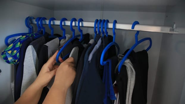 salvador, bahia / brazil - may 7, 2020: hands are seen picking up children's clothes on a hanger.