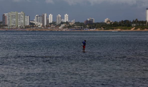 salvador, bahia / brazil - january 24, 2019: fisherman is seen with his fishing rod on Itapua beach in the city of Salvador.
