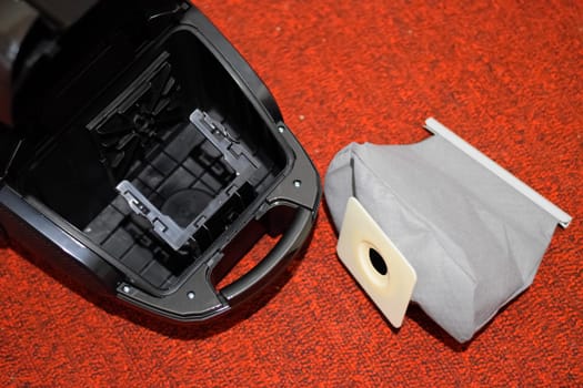 A vacuum cleaner with a set of brushes and bags. A vacuum cleaner on the red carpet.