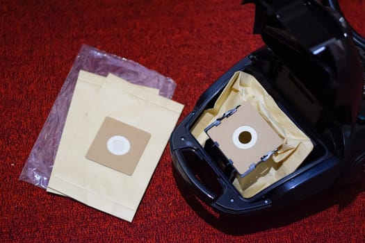 A vacuum cleaner with a set of brushes and bags. A vacuum cleaner on the red carpet.