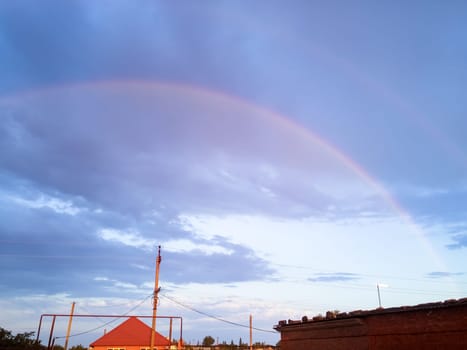 Rainbow over the village. Rainbow after rain.