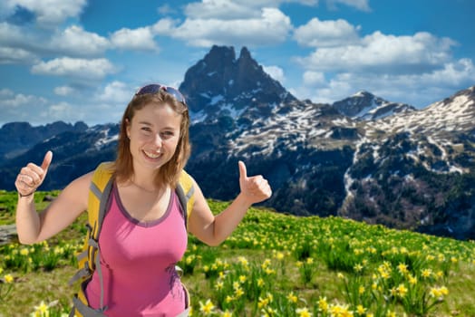 pretty hiker woman with Pic du Midi Ossau and daffodils in springtime, french Pyrenees.