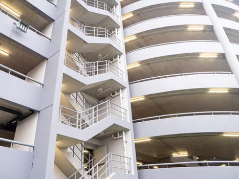 walking on the stair on the side of a white multi storey parking lots building