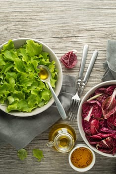 Healthy red and green lettuce salad meals on wooden table background. Eating fresh radicchio and young lettuce with dressing sauce