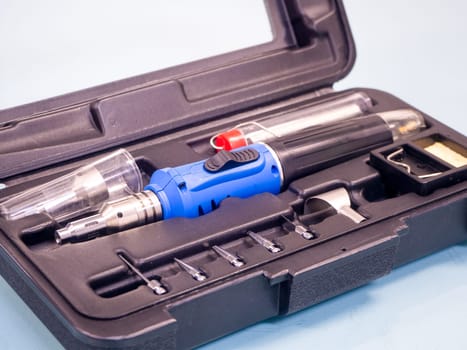 Gas soldering iron in black box isolated on white background.