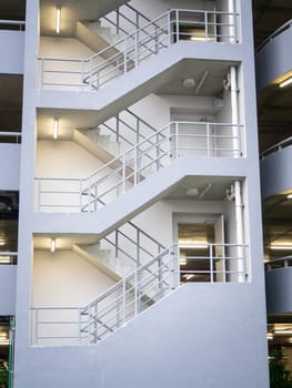 walking on the stair on the side of a white multi storey parking lots building