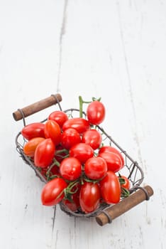 Red cherry tomatoes on a white textured background, empty space for text.
