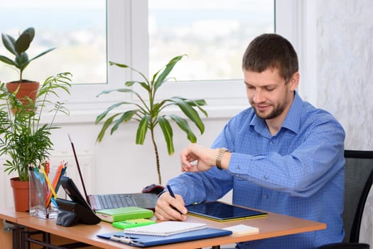 A businessman looks at a watch while in the office at his workplace