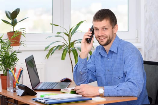 Confident office specialist talking on the phone and looked into the frame