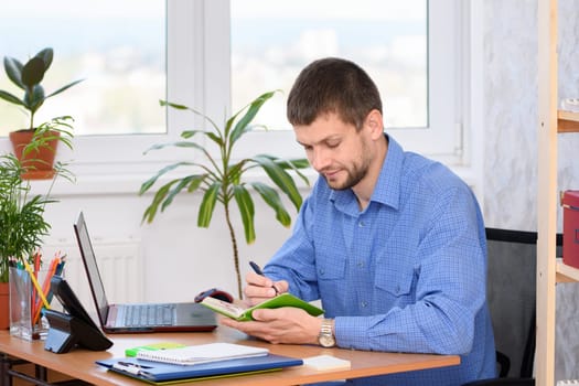 Business man in the office writes notes in a notebook