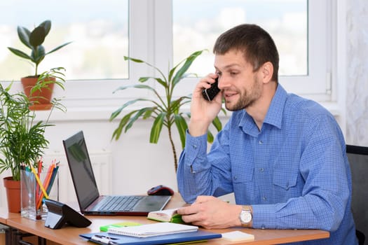 A man in the office talking on the phone