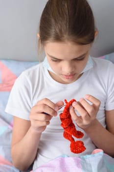 A girl in quarantine is engaged in knitting toys