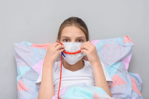 Girl shows a smile on her face made of threads, doing knitting at home in self-isolation mode