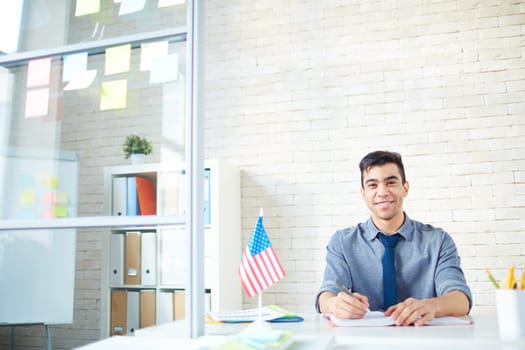 Happy young businessman looking at camera in office