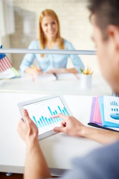 Young businessman using touchpad on background of female