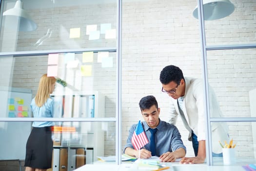 Young employees consulting while reading document at workplace