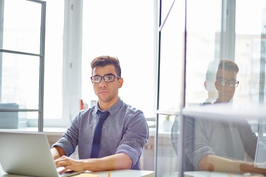 Calm businessman in casualwear networking by desk in office