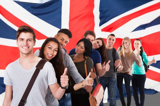 Portrait of college students gesturing thumbs up while standing in a line over white background